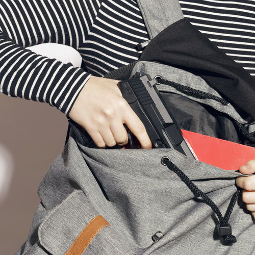 A Woman Pulls a Gun From a Backpack.