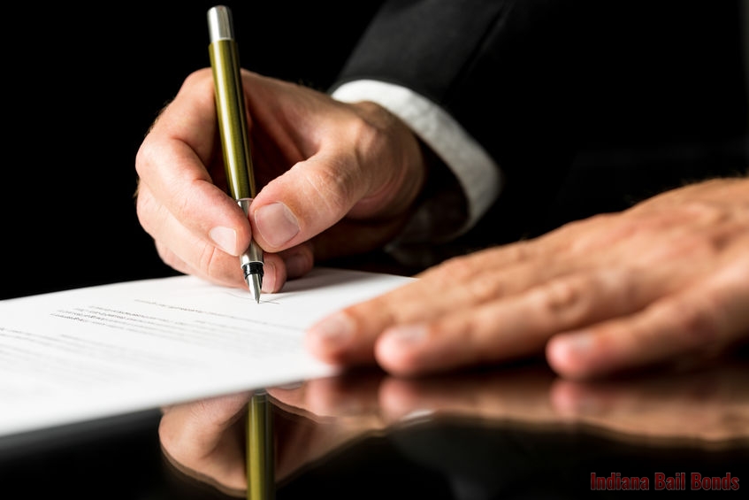 Closeup of male hand signing legal or insurance document on black desk with reflection.