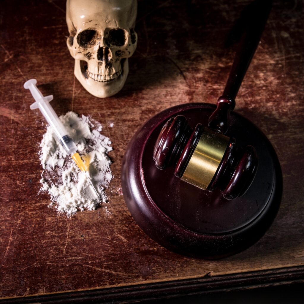 drugs next to a skull and hammer signifying death and law